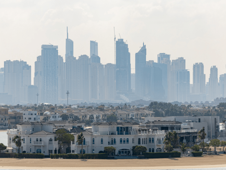 Residential skyscraper buildings beyond luxury villas on the waterfront of the Palm Jumeirah in Dubai.