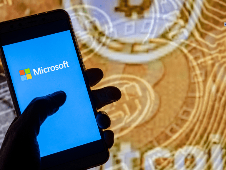 In this photo illustration the Microsoft logo is seen on the screen of a smartphone with a bitcoin cryptocurrency logo in the background.