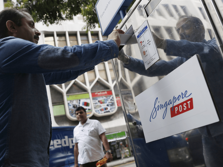 A man drops a letter into a SingPost mailbox. (Photo: Reuters)